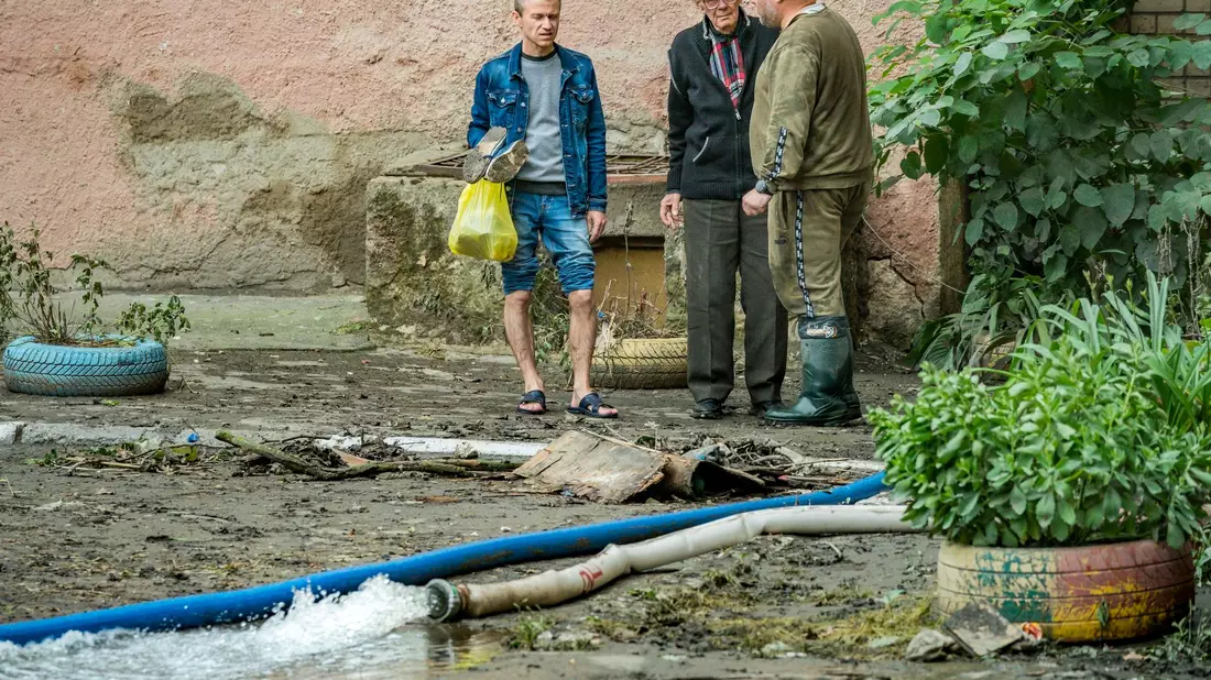 Anwohner stehen in der Nähe von Schläuchen, die das Wasser nach dem Hochwasser des Dnepr-Flusses aufgrund der Zerstörung des Nova-Kachowka-Damms flussaufwärts aus ihren Häusern pumpen. - Bild: Celestino Arce Lavin/ZUMA Press Wire/dpa