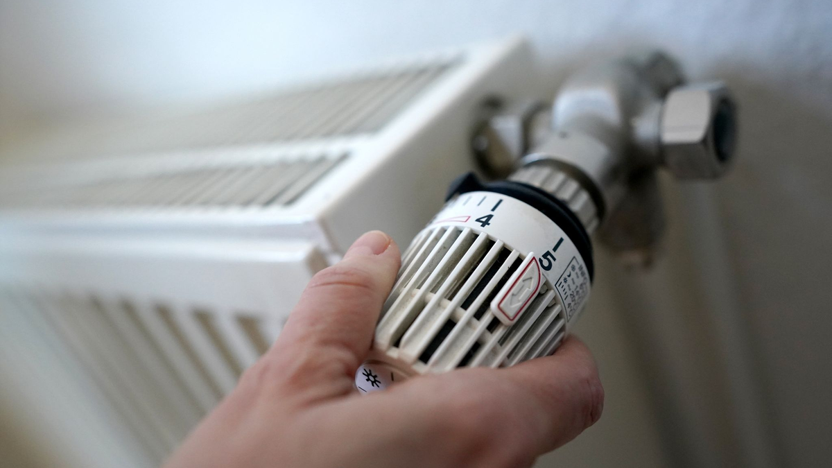 Eine Frau dreht an einem Heizungsthermostat. - Foto: Marcus Brandt/dpa