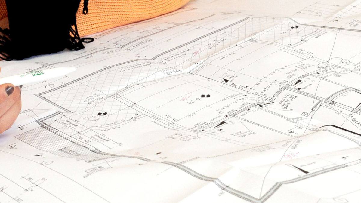 Eine Bauzeichnerin vor einem Bauplan. Die Bauindustrie fordert bessere digitale Lösungen für die Verwaltung. - Foto: Carsten Rehder/dpa