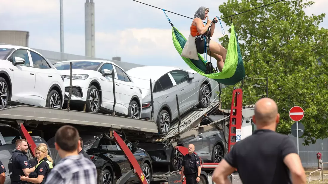 Eine Aktivistin hängt an einem Seil über der Liefereinfahrt ins VW-Stammwerk in Wolfsburg. - Bild: Bodo Marks/dpa
