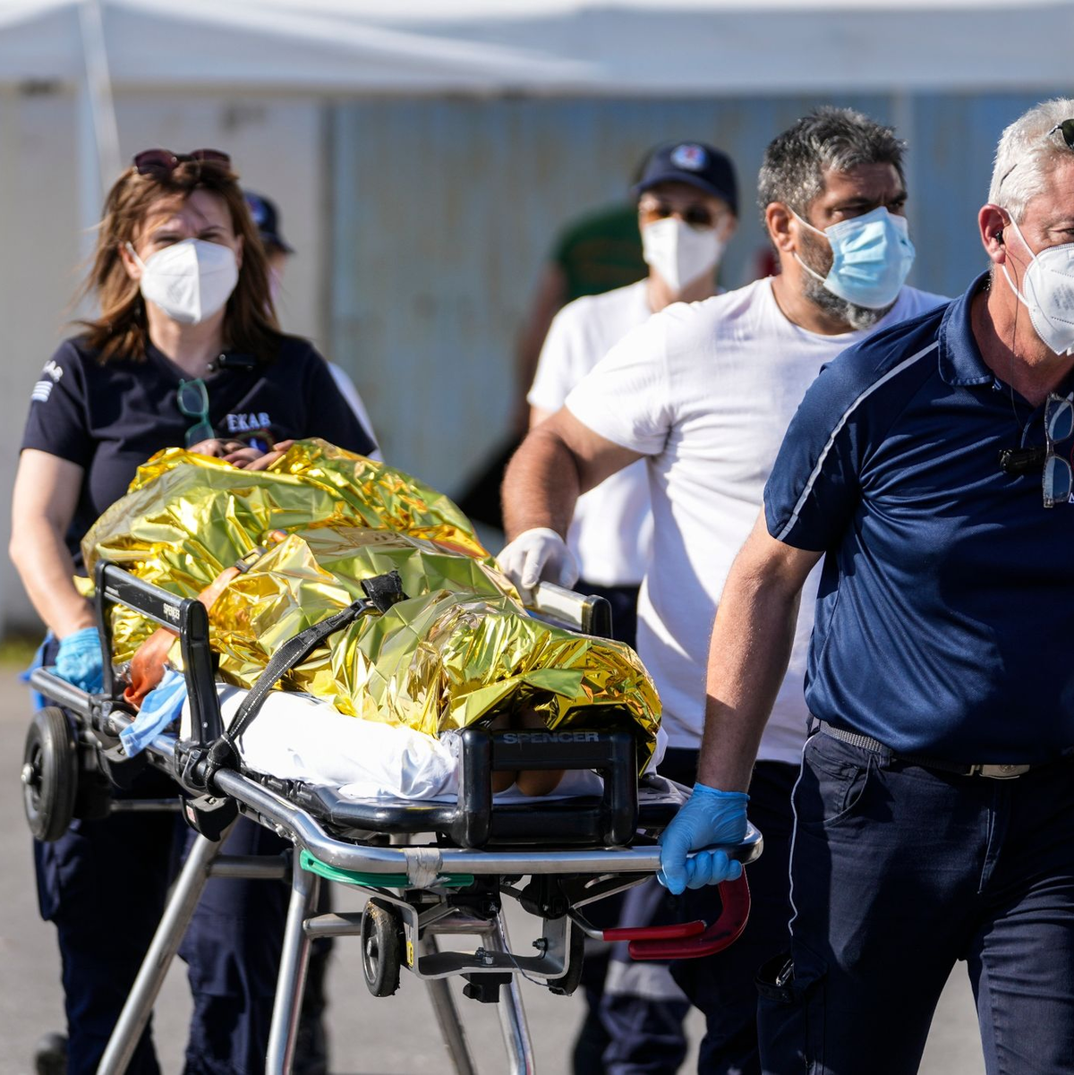Sanitäter transportieren einen verletzten Überlebenden des Bootsunglücks zu einem Krankenwagen im Hafen der griechischen Stadt Kalamata. - Foto: Thanassis Stavrakis/AP/dpa