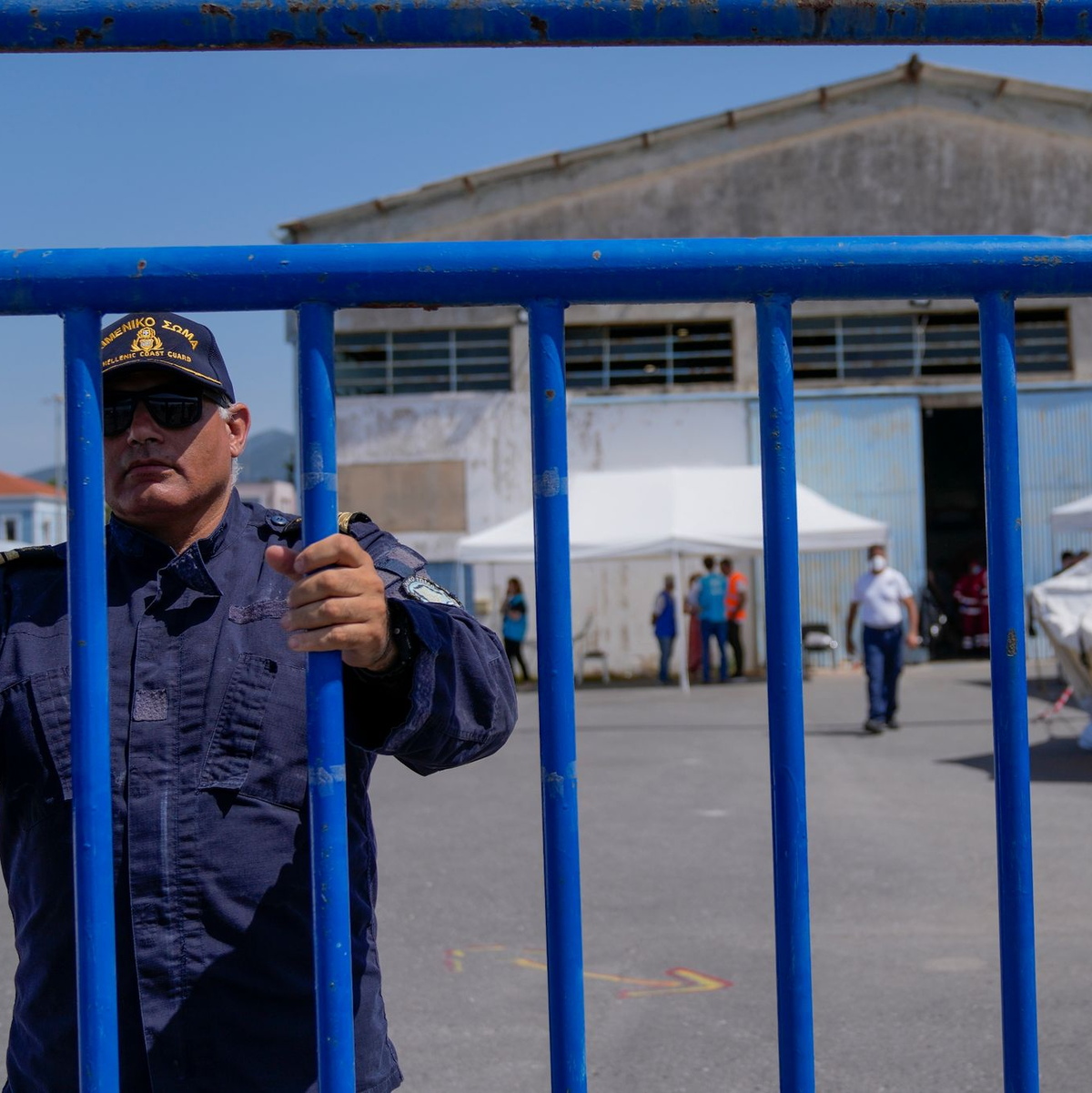 Ein Offizier der Küstenwache am Eingang des Flüchtlingslagers nahe Athen. - Foto: Thanassis Stavrakis/AP/dpa