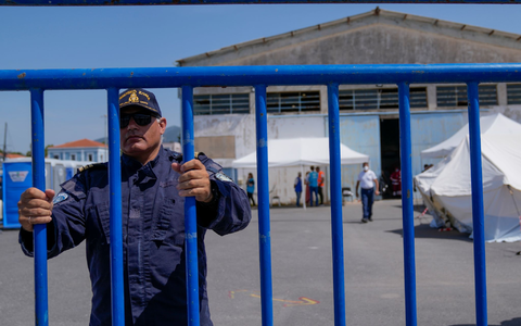 Ein Offizier der Küstenwache am Eingang des Flüchtlingslagers nahe Athen. - Foto: Thanassis Stavrakis/AP/dpa