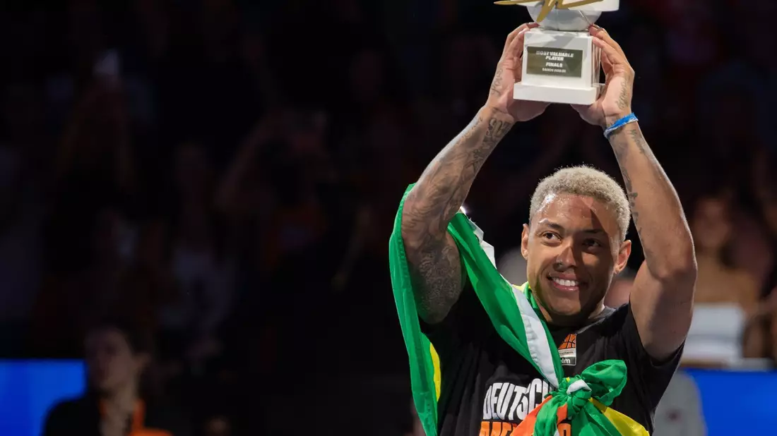 Ulms Yago dos Santos reckt die Trophäe für den wertvollsten Spieler der Playoffs hoch. - Bild: Stefan Puchner/dpa