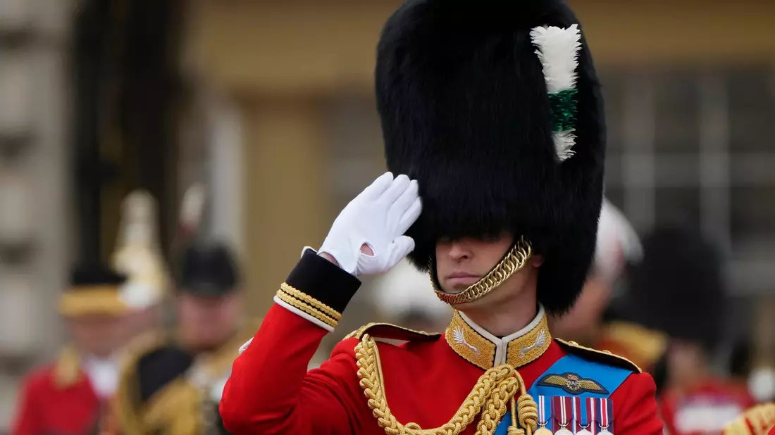 Thronfolger Prinz William trägt Bärenfellmütze und salutiert. - Bild: Alastair Grant/AP/dpa