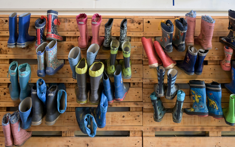 Gummistiefel hängen an der Palettenwand einer Kindertagesstätte in Halle (Saale). In Deutschland fehlen Erzieherinnen und Erzieher. - Foto: Heiko Rebsch/dpa