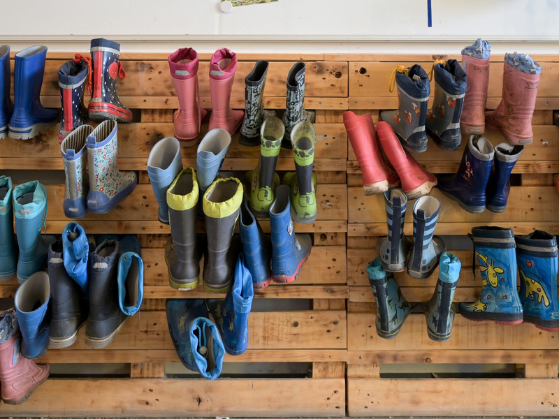 Gummistiefel hängen an der Palettenwand einer Kindertagesstätte in Halle (Saale). In Deutschland fehlen Erzieherinnen und Erzieher. - Foto: Heiko Rebsch/dpa