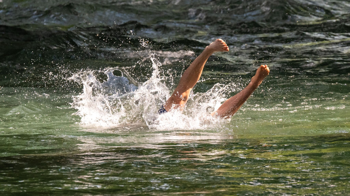 Ein junger Mann erfrischt sich mit einem Sprung in den Eisbach im Englischen Garten in München. - Foto: Peter Kneffel/dpa
