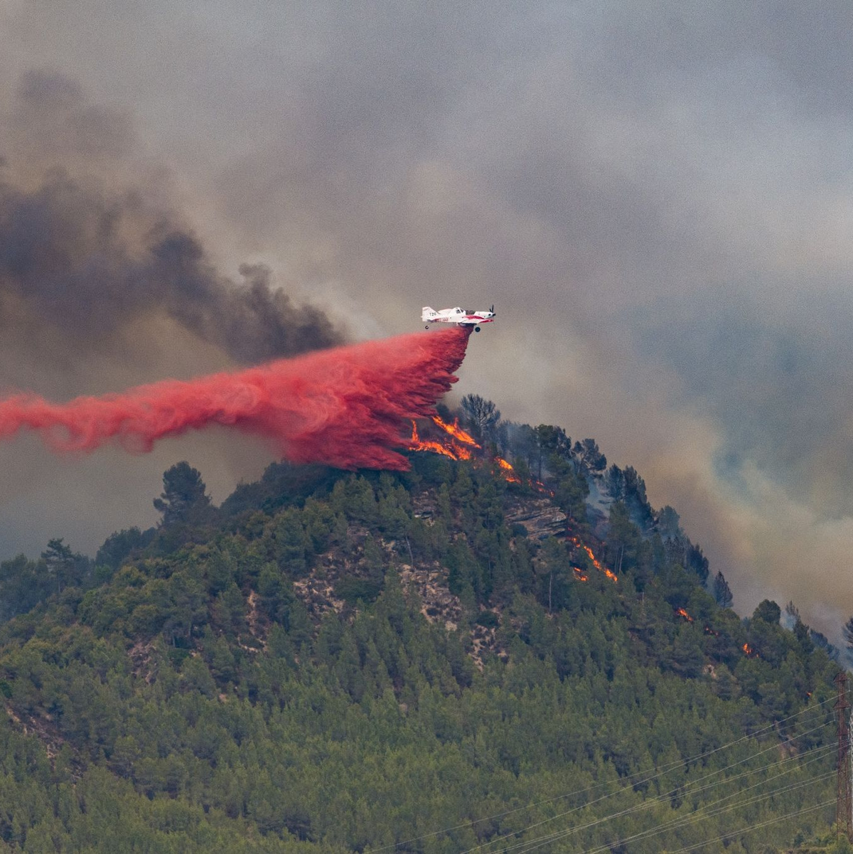 Ein Flugzeug wirft Löschmittel auf die Flammen eines Waldbrandes im spanischen Castellgali. - Foto: Lorena Sopêna/EUROPA PRESS/dpa