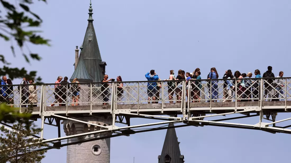 Touristen stehen auf der Marienbrücke vor dem Schloss Neuschwanstein. - Bild: Karl-Josef Hildenbrand/dpa