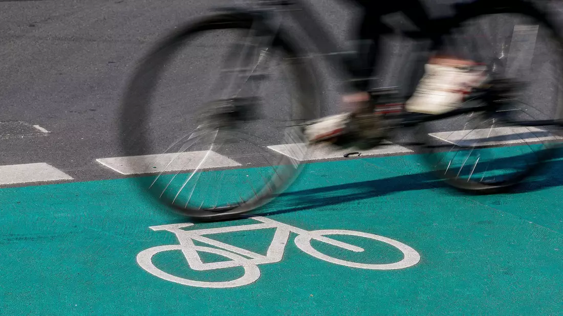 Eine Radfahrerin fährt in Leipzig über einen grün eingefärbten Radweg. - Bild: Jan Woitas/dpa