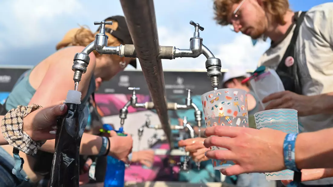Besucher füllen beim Hurricane Festival ihre Becher und Trinkflaschen mit Wasser auf. In Deutschland steigen die Temperaturen - und die Ozon-Werte. - Bild: Lars Penning/dpa