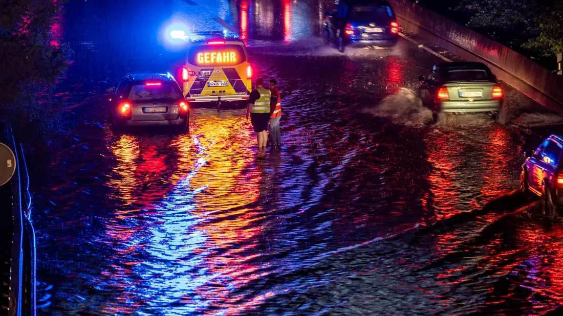 Teilabschnitte der A59 in Duisburg sind nach stundenlangen Regenfällen überschwemmt, Autos fahren durch die Wassermassen. - Bild: Christoph Reichwein/dpa