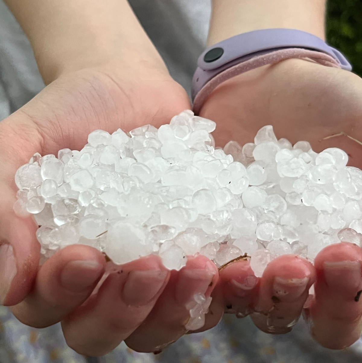 Eine Jugendliche hält nach einem Unwetter in Gilching Hagelkörner in der Hand. - Foto: Christoph Trost/dpa