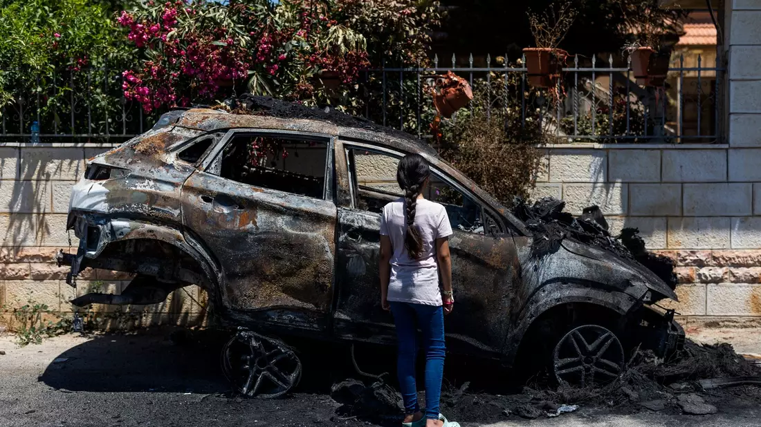 Ein Mädchen steht in Turmus Aya im Westjordanland neben einem Auto, das infolge eines Brandanschlags durch jüdische Siedler zerstört worden ist. - Bild: Ilia Yefimovich/dpa