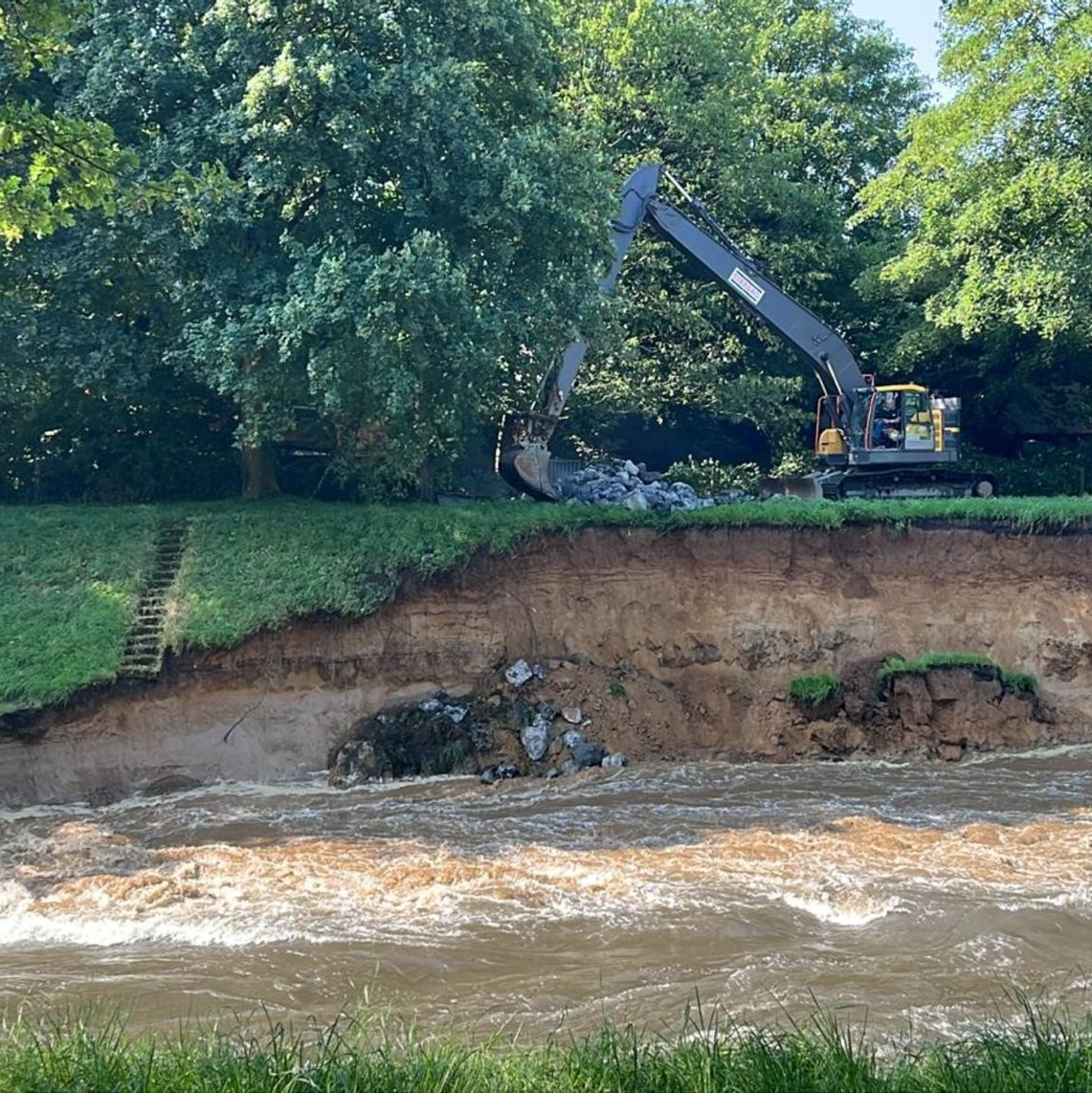 Durch starke Regenfälle ist der Emscherdeich in Dinslaken instabil geworden. Ein Bagger arbeitet, um ihn zu sichern. - Foto: Alex Forstreuter/dpa