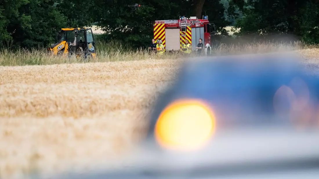 Polizisten arbeiten an der Unfallstelle, die sich hinter dem Feuerwehrfahrzeug befindet. - Bild: Philipp Schulze/dpa
