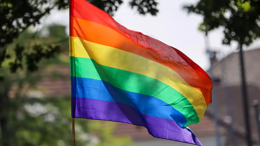 Eine Regenbogenfahne weht im Wind. - Bild: Focke Strangmann/dpa