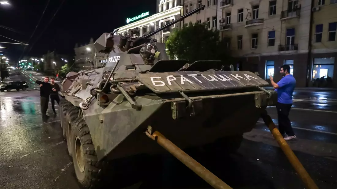 Menschen gehen um ein gepanzertes Fahrzeug des Militärunternehmens Wagner Group mit der Aufschrift «Brother» herum, bevor sie ein Gelände am Hauptsitz des Südlichen Militärbezirks auf einer Straße in Rostow am Don verlassen. - Bild: ---/AP/dpa