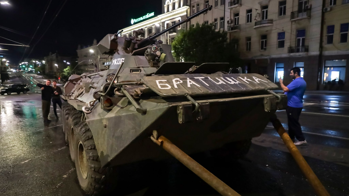 Menschen gehen um ein gepanzertes Fahrzeug des Militärunternehmens Wagner Group mit der Aufschrift «Brother» herum, bevor sie ein Gelände am Hauptsitz des Südlichen Militärbezirks auf einer Straße in Rostow am Don verlassen. - Foto: ---/AP/dpa