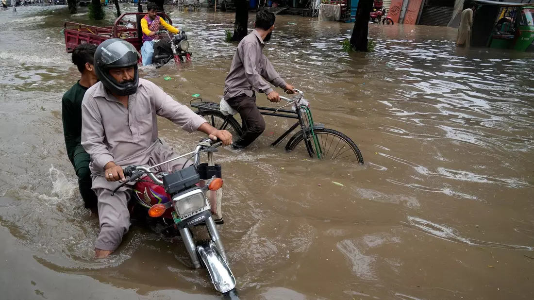 Motorradfahrer auf einer überschwemmten Straße im pakistanischen Lahore. - Bild: K.M. Chaudary/AP/dpa
