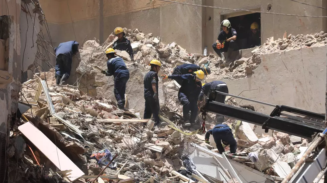 Mitglieder des ägyptischen Zivilschutzes bei den Überresten des eingestürzten 13-stöckigen Wohngebäudes in Alexandria. - Bild: Stringer/dpa