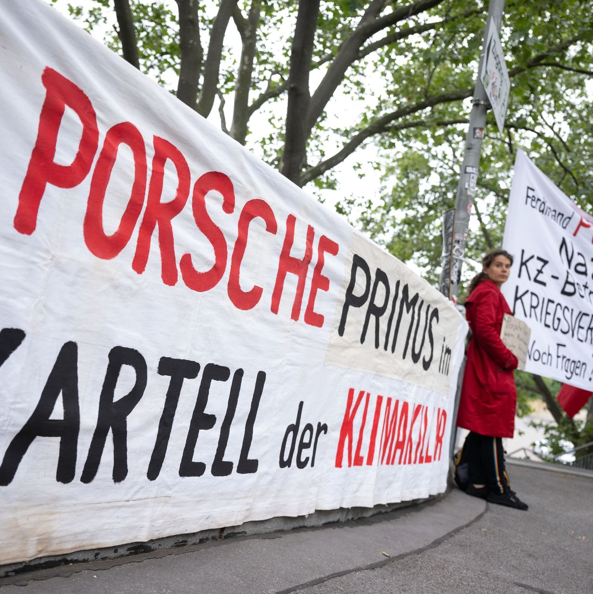 Demonstranten mit Plakaten vor Beginn der Porsche-Hauptversammlung in Stuttgart. - Foto: Marijan Murat/dpa