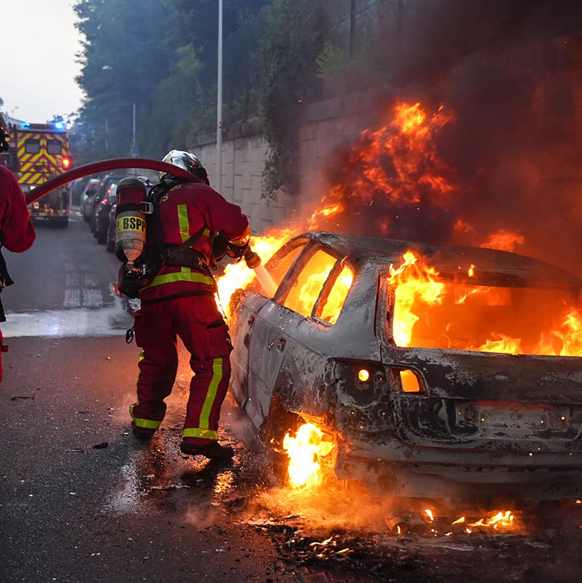 Feuerwehrleute löschen ein brennendes Auto am Rande der Ausschreitungen westlich von Paris. - Foto: Zakaria Abdelkafi/AFP/dpa