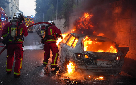 Feuerwehrleute löschen ein brennendes Auto am Rande der Ausschreitungen westlich von Paris. - Foto: Zakaria Abdelkafi/AFP/dpa