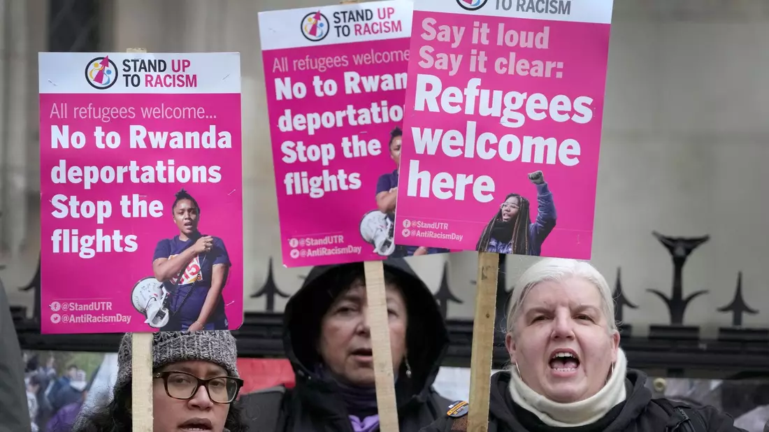 «Stand Up To Racism»-Aktivisten mit Plakaten vor dem High Court in London (Archivbild). - Bild: Kirsty Wigglesworth/AP/dpa