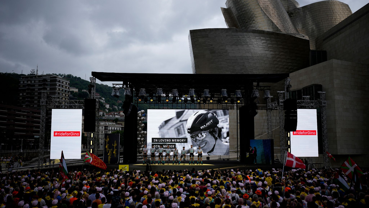 Zuschauer und Radprofis des Teams Bahrain-Victorious legen eine Schweigeminute zu Ehren des Schweizers Gino Mader ein. - Foto: Daniel Cole/AP