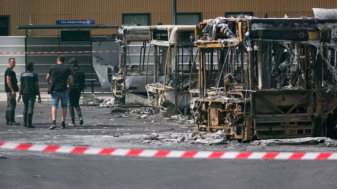 Polizeiermittler vor ausgebrannten Bussen in Aubervilliers. - Bild: Michel Euler/AP/dpa