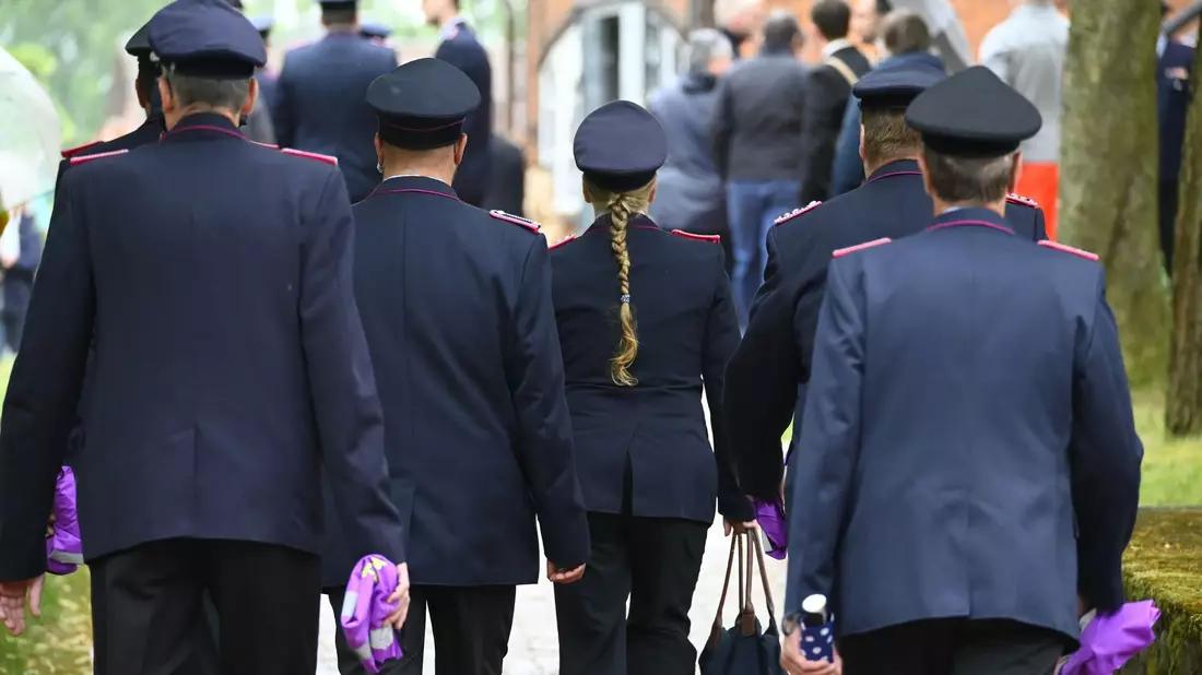 Feuerwehrleute in Uniform vor Beginn des Gottesdienstes in Toppenstedt. - Bild: Jonas Walzberg/dpa