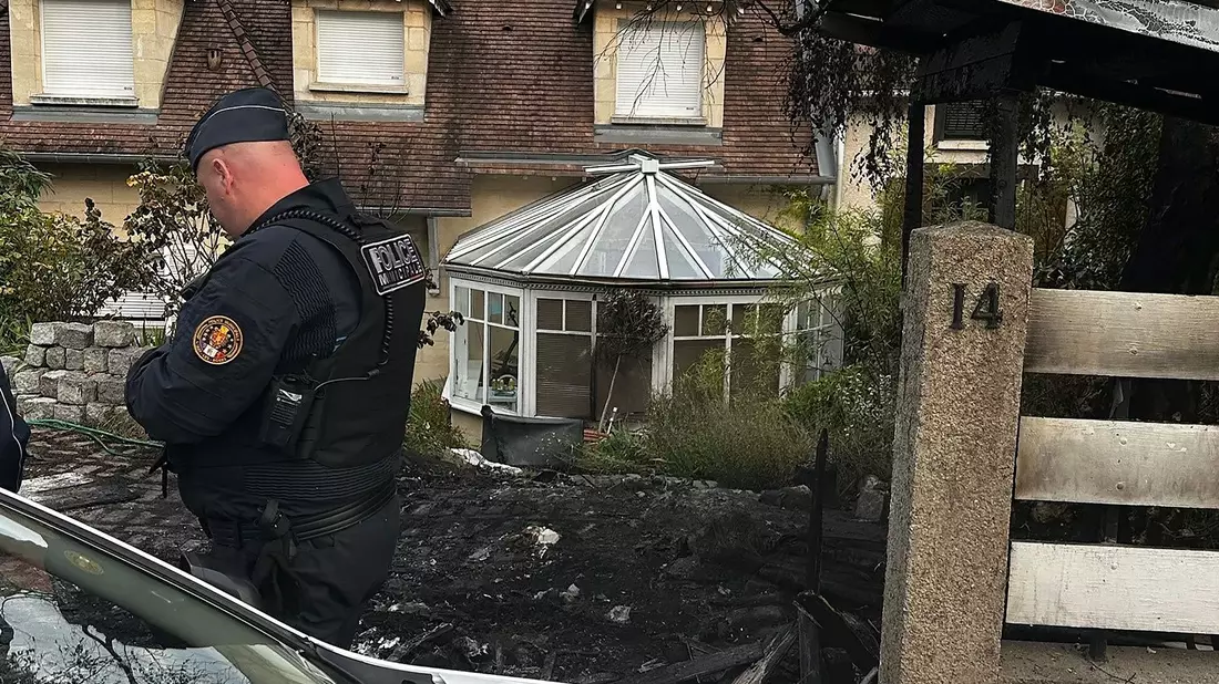 Ein Polizist steht vor dem Haus des Bürgermeisters Vincent Jeanbrun. Randalierer hatten das Haus in der Nacht mit einem Auto gerammt und Feuer gelegt. - Bild: Nassim Gomri/AFP/dpa