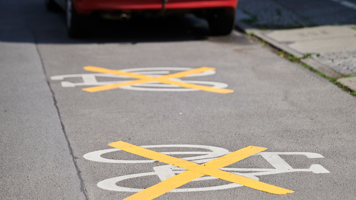 Auf der Ollenhauer Straße sind die Zeichen für den Radweg mit gelben Kreuzen zugeklebt und Autos parken darauf. Der Radweg existiert nicht mehr. - Foto: Annette Riedl/dpa