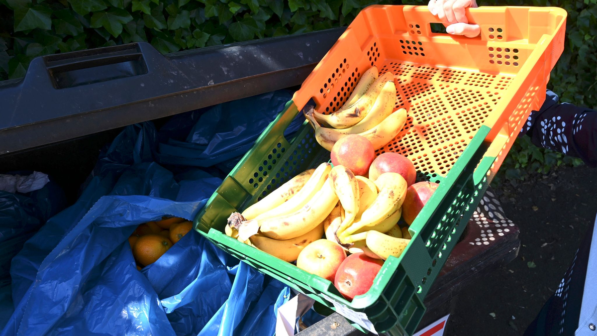 Ein Mitarbeiter eines Supermarktes bringt Obst zu einem Müllcontainer. - Foto: Carmen Jaspersen/dpa