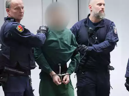 Der Angeklagte Ibrahim A. wird von Justizbeamten an seinen Platz im Gerichtssaal gebracht. - Foto: Christian Charisius/dpa