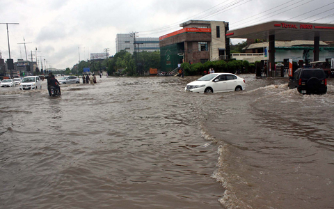 Pendler fahren in Lahore eine überschwemmte Straße entlang. - Foto: Ppi/PPI via ZUMA Press Wire/dpa