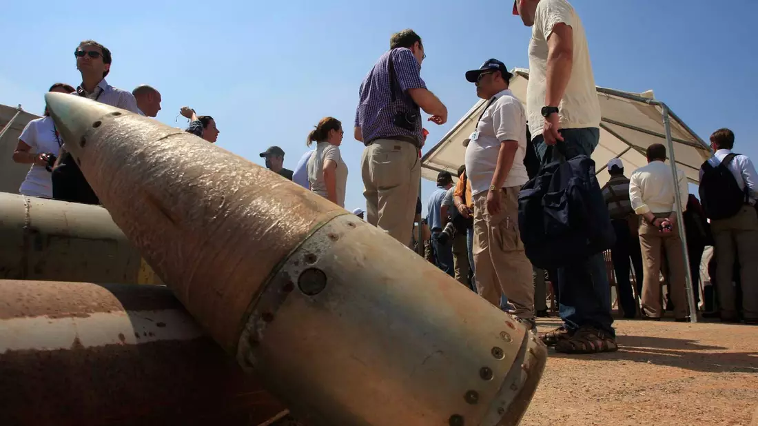 Aktivisten und Mitglieder internationaler Delegationen stehen neben Streubombeneinheiten während eines Besuchs auf einem libanesischen Militärstützpunkt. - Bild: Mohammad Zaatari/ap/dpa