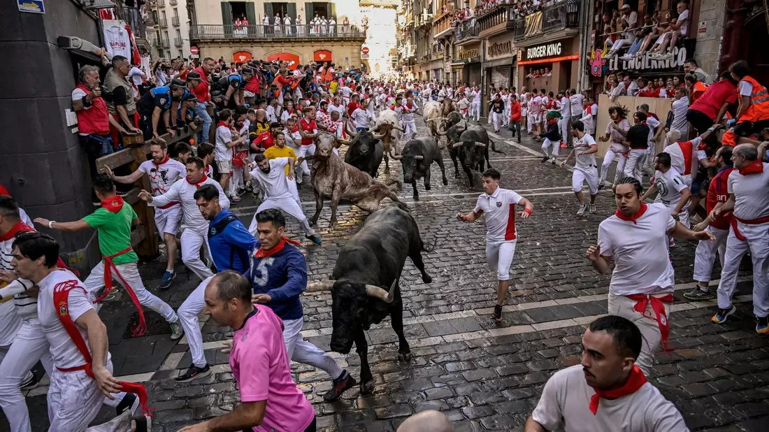 Viele Läufer halten traditionell eine aufgerollte Zeitung in der Hand, mit der sie während der Hatz anderen Läufern Zeichen geben und den Stieren auch leichte Klapse geben können, um sie zu dirigieren. - Bild: Alvaro Barrientos/AP