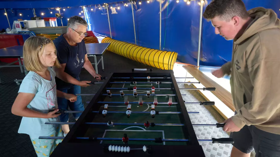 Eine Familie spielt in dem Zirkuszelt Tischfussball. - Bild: Thomas Frey/dpa