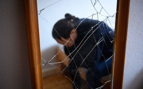 Eine Frau sitzt neben einem gesprungenen Spiegel auf einem Bett und hält ihren Kopf in den Händen. (Symbolbild) - Foto: Jonas Walzberg/dpa