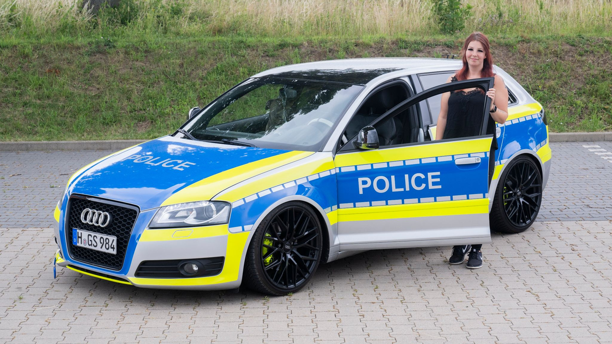 Die Autotunerin Svenja Geertz steht neben ihrem  Audi, der ähnlich wie ein Polizeifahrzeug foliert ist. - Foto: Julian Stratenschulte/dpa