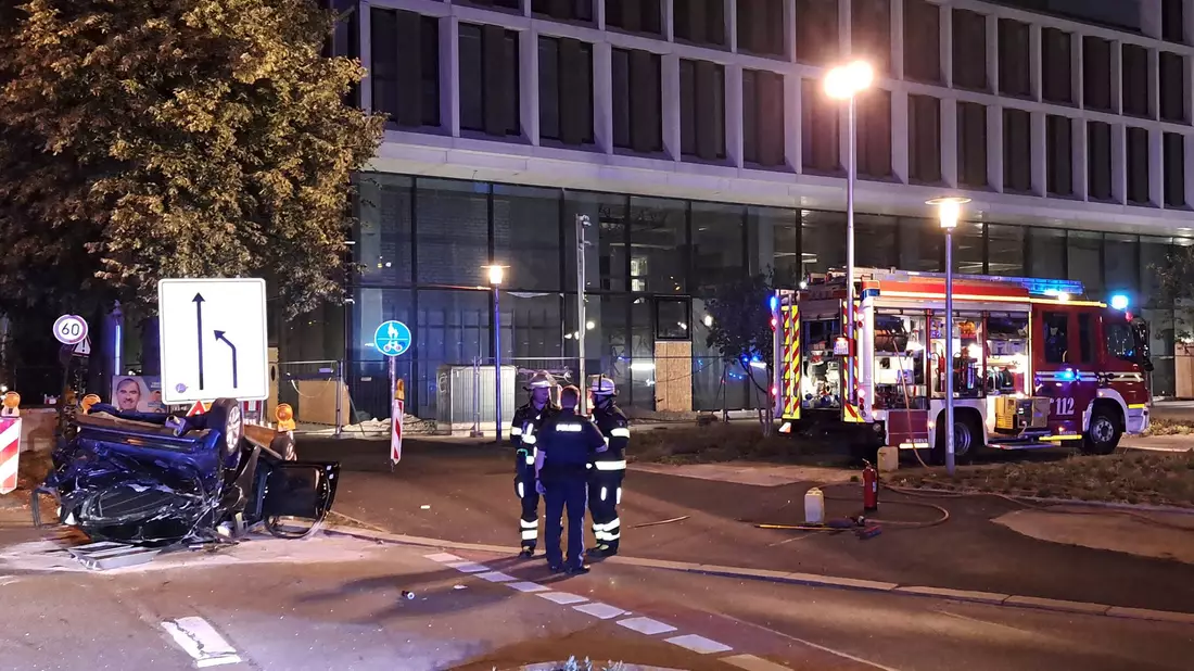 Einsatzkräfte der Feuerwehr und Polizei stehen neben einem zerstörtem Wagen an der Unfallstelle in München. - Bild: -/Berufsfeuerwehr München/dpa
