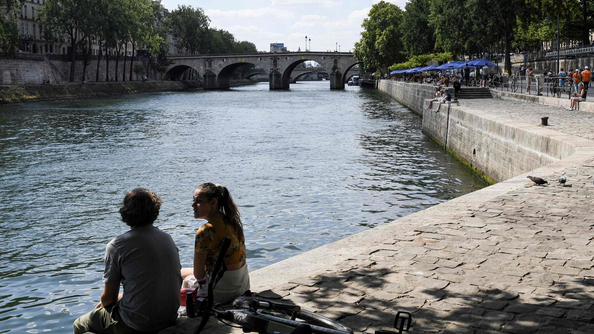 Zwei junge Leute sitzen am Ufer der Seine in Paris. - Foto: Alain Jocard/AFP/dpa