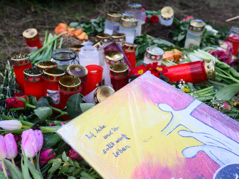 Blumen und Kerzen erinnern in Wunstorf-Blumenau nahe Hannover an den ermordeten 14-jährigen Jungen. - Foto: Julian Stratenschulte/dpa