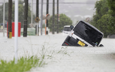 Ein Fahrzeug steckt auf einer überfluteten Straße in der Präfektur Fukuoka fest. - Foto: Uncredited/Kyodo News/AP