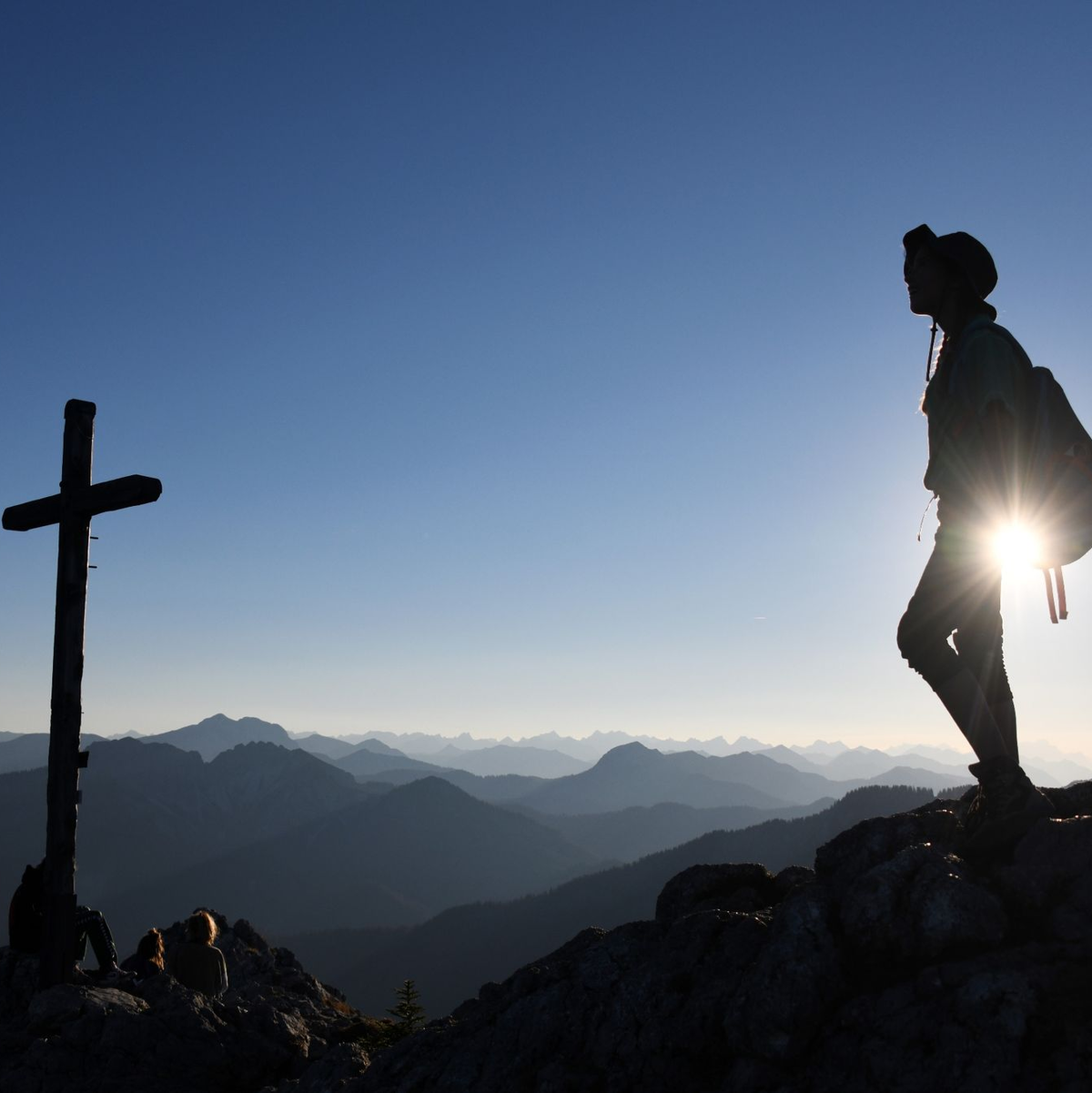 Eine Ausflüglerin genießt den Blick am Gipfelkreuz des Taubensteins. - Foto: Tobias Hase/dpa