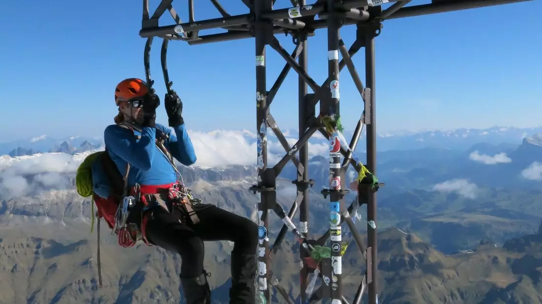 Ein Bergsteiger macht an seinen Eisgeräten einen Klimmzug am Gipfelkreuz der Marmolada. - Bild: Elke Richter/dpa