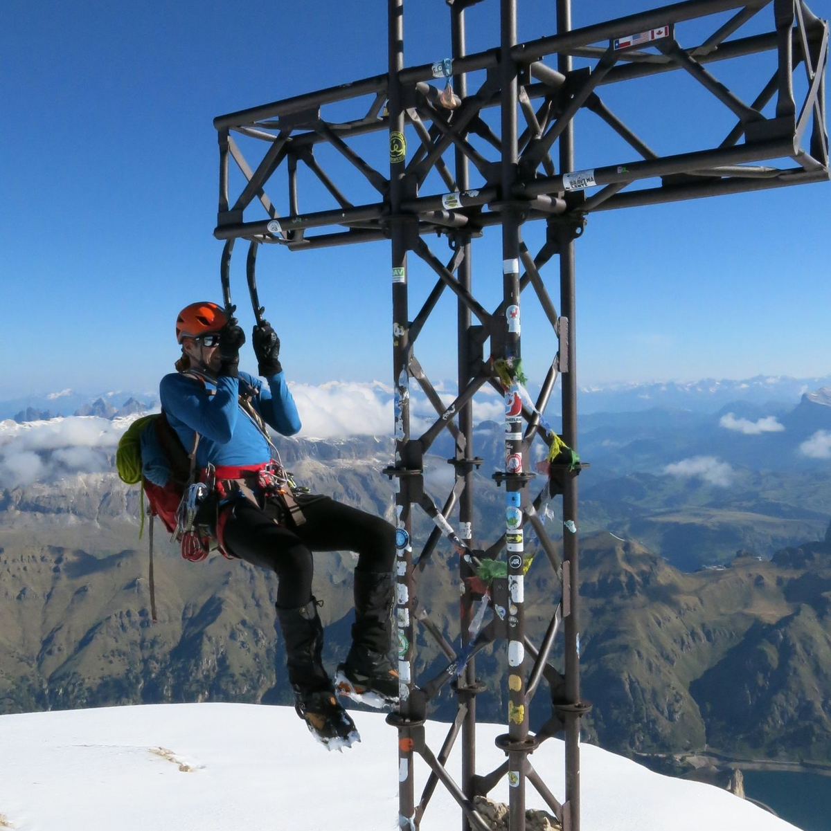 Ein Bergsteiger macht an seinen Eisgeräten einen Klimmzug am Gipfelkreuz der Marmolada. - Foto: Elke Richter/dpa
